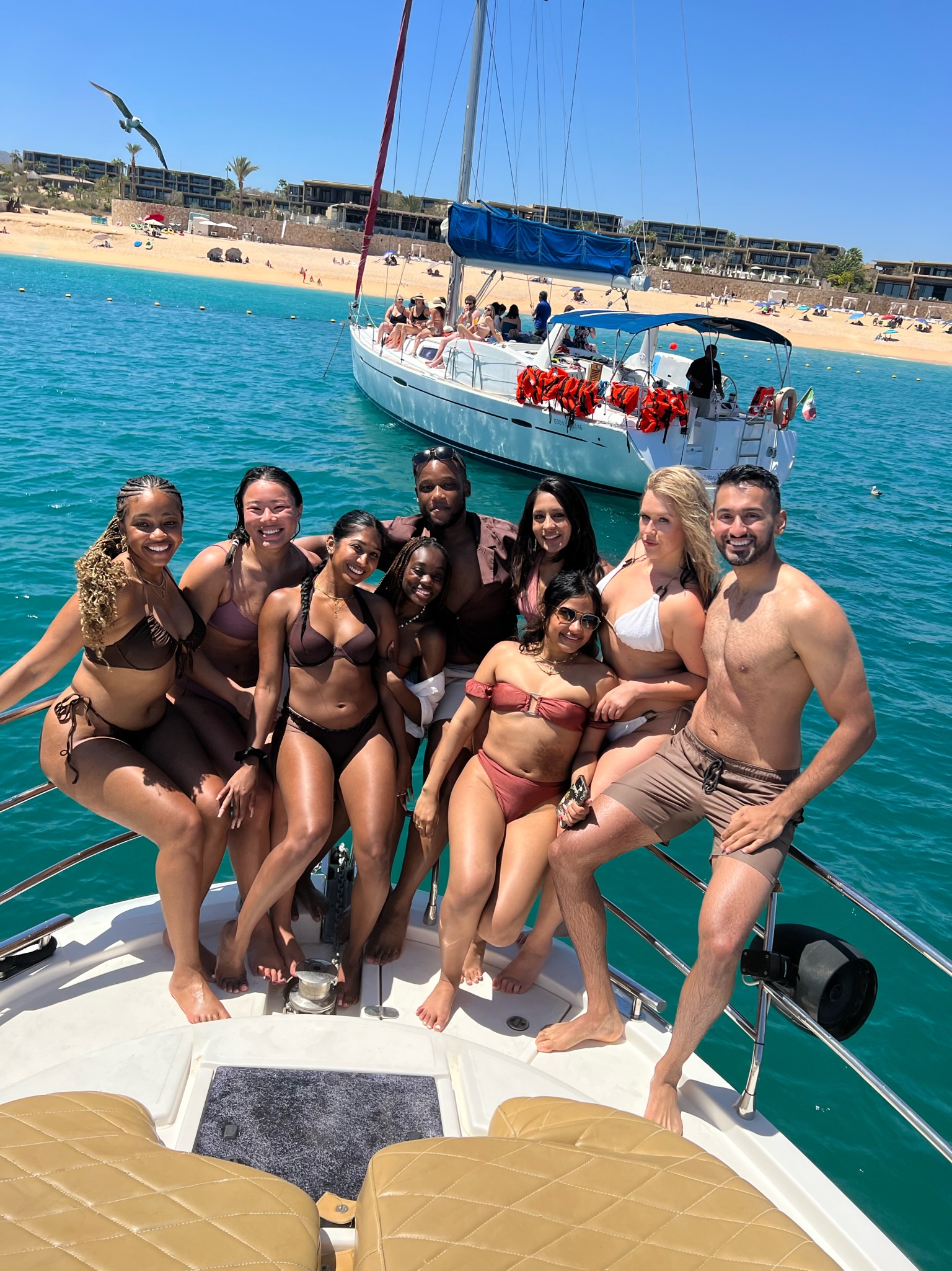 Group of friends sitting and smiling on the bough of a yacht 