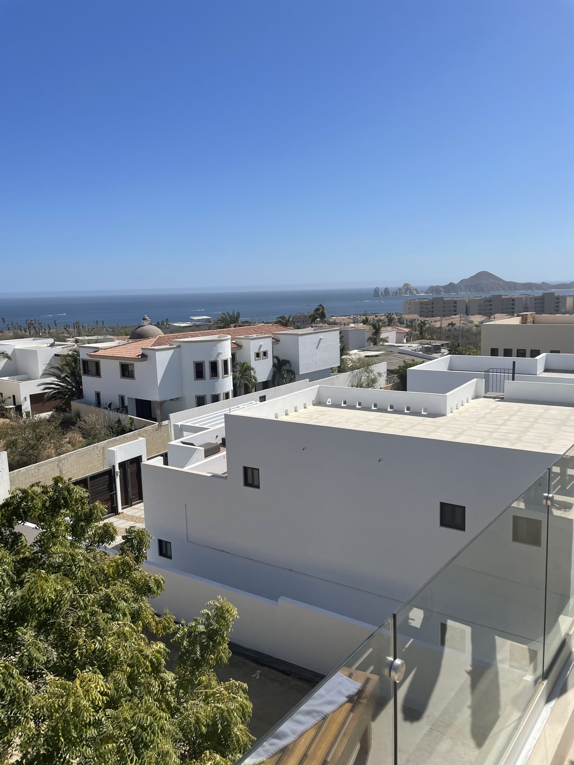 View from the Airbnb in Cabo of the pretty houses and then the dark blue ocean meeting the sky 